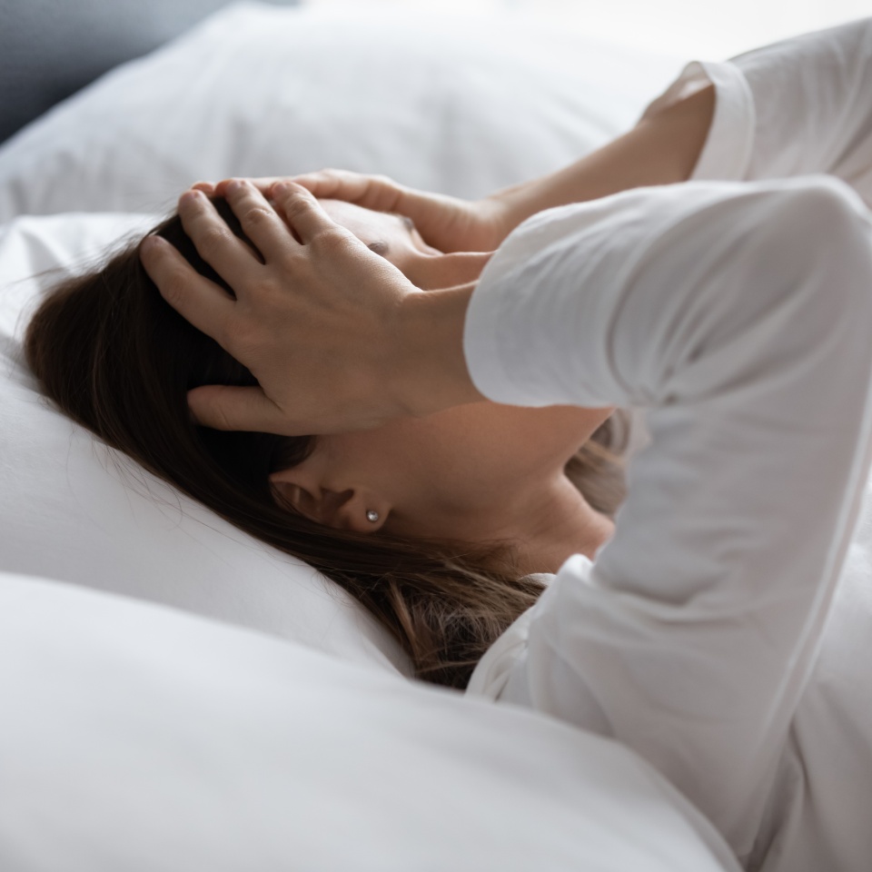 Close up woman lying in bed woke up in early morning touch head with palms feels tired not enough of rest, insomnia sleep disorder anxious by personal problems, unhealthy migraine and headache concept