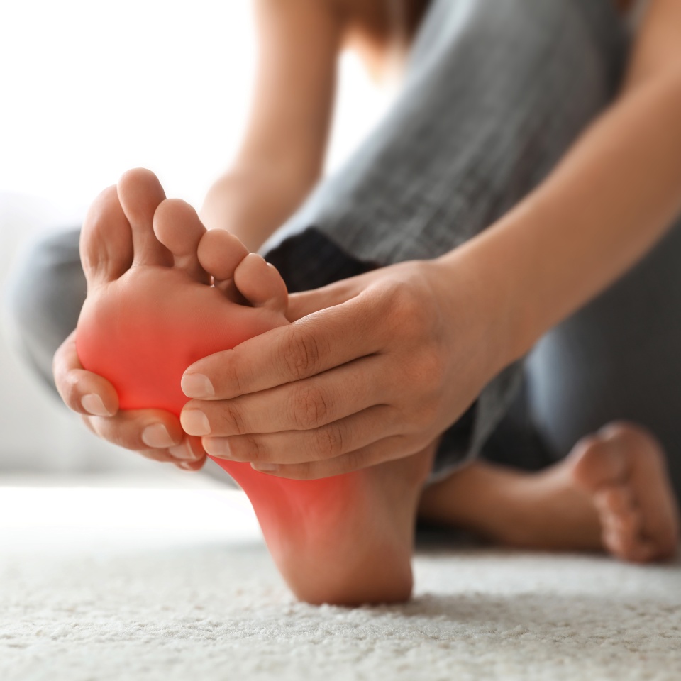 Woman suffering from foot pain at home, closeup