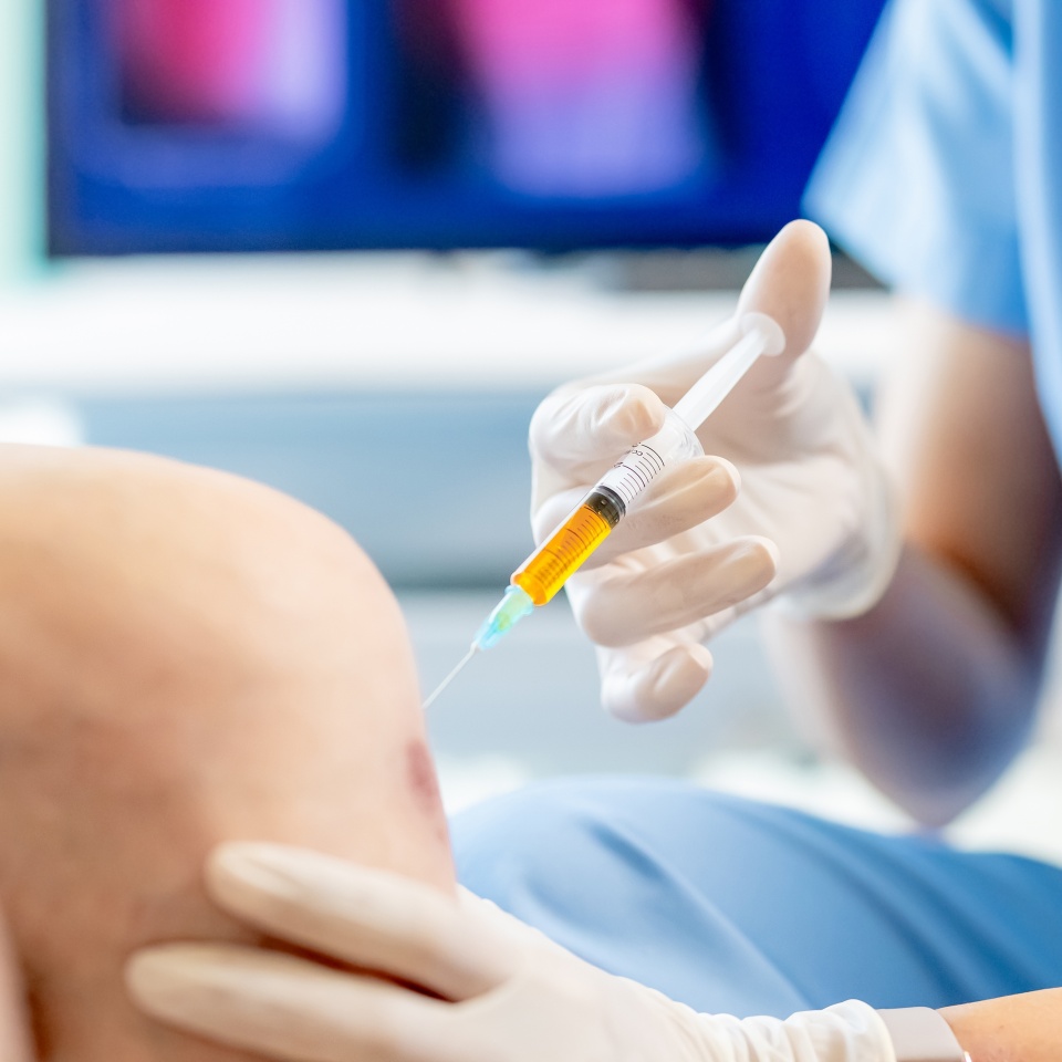 close up of asian female doctor make injection to male elderly senior patient in knee at hospital
