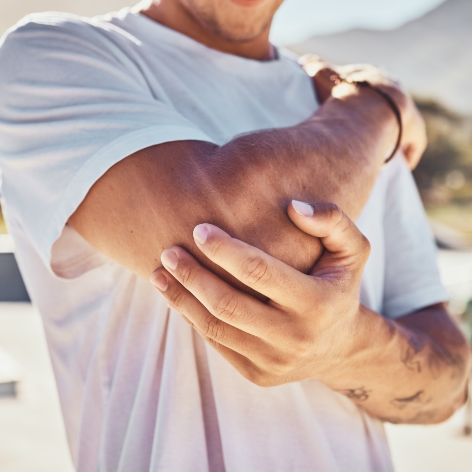 Elbow, joint pain and man, outdoor accident and urban park, emergency and first aid, risk and body problem. Broken arm, bone health and guy in pain, physical therapy injury and muscle inflammation