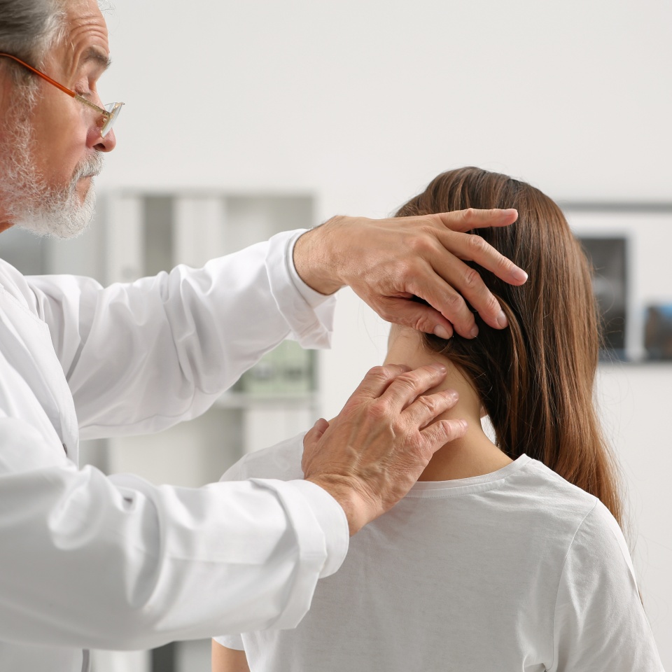 Professional orthopedist examining patient's neck in clinic