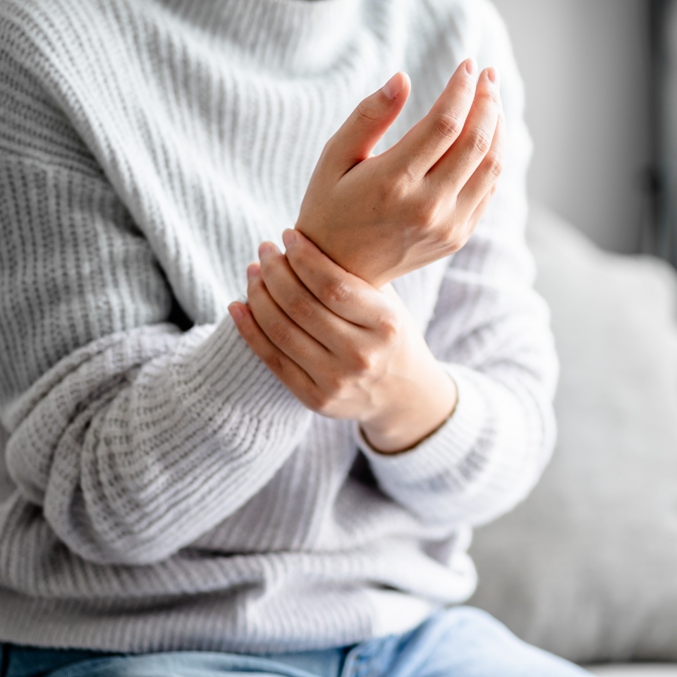Close up view of a Young woman massaging her hand for relieve feeling wrist pain, joints aches, arthritis inflammation, peripheral neuropathies, muscle strain.