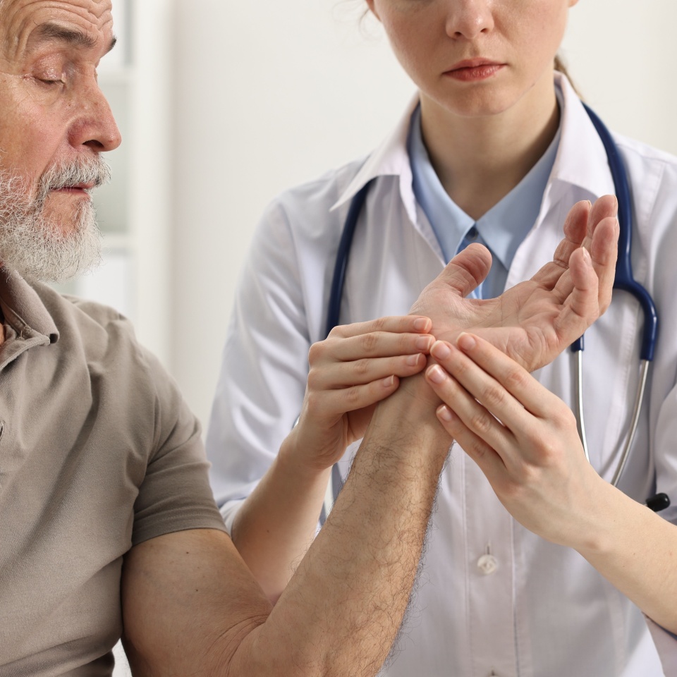 Arthritis symptoms. Doctor examining patient's hand in hospital