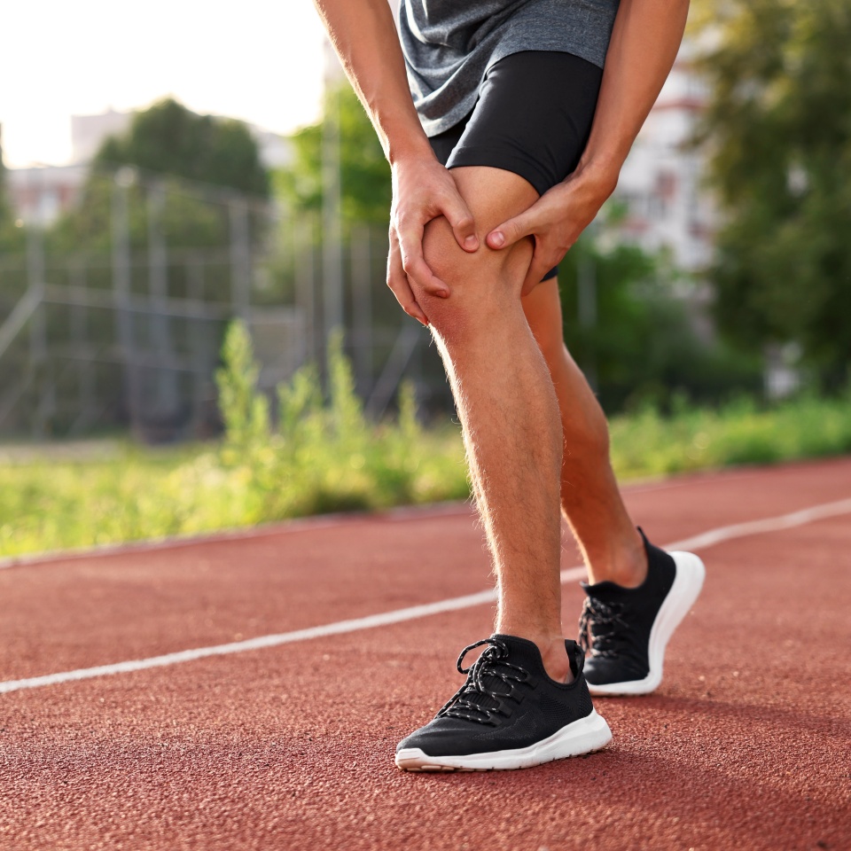Sportsman with leg injury suffering from knee pain at stadium, closeup. Space for text