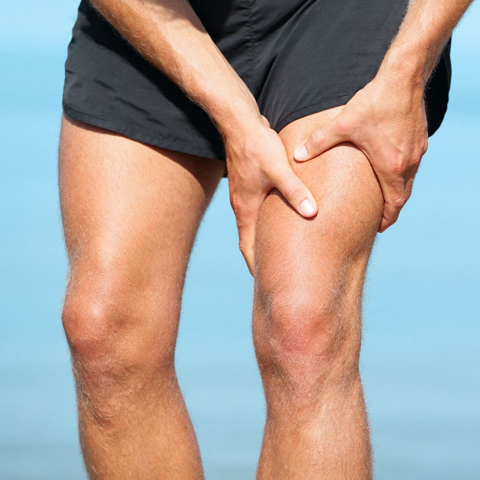 Sports injury muscle cramp pain fit runner man athlete holding painful thigh leg