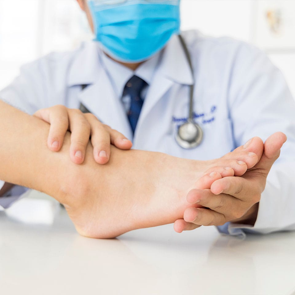 The orthopedic doctor or surgeon in white gown examined the patient with foot pain problem