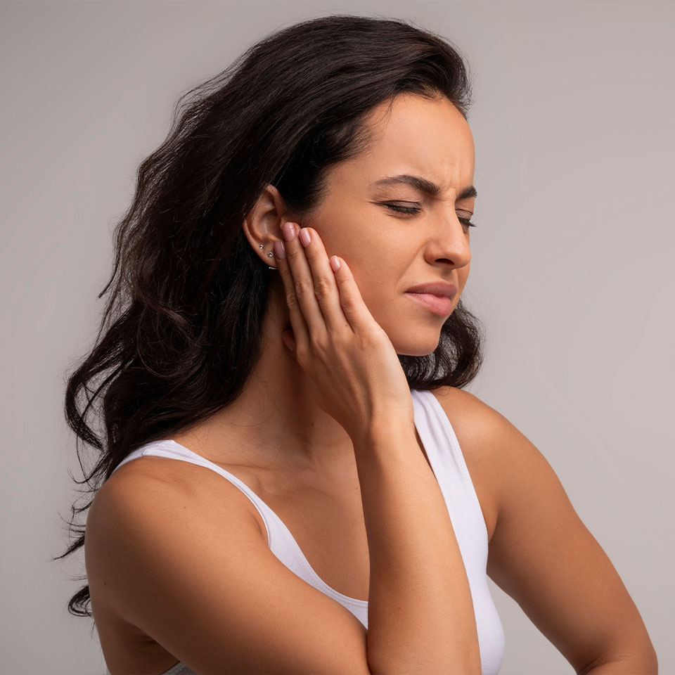 Profile of sick brunette young woman having ear pain, touching her painful cheek