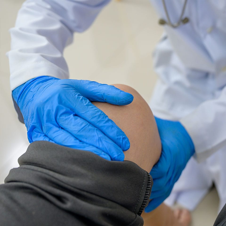 A doctor is examining the knee of a woman who has a knee injury