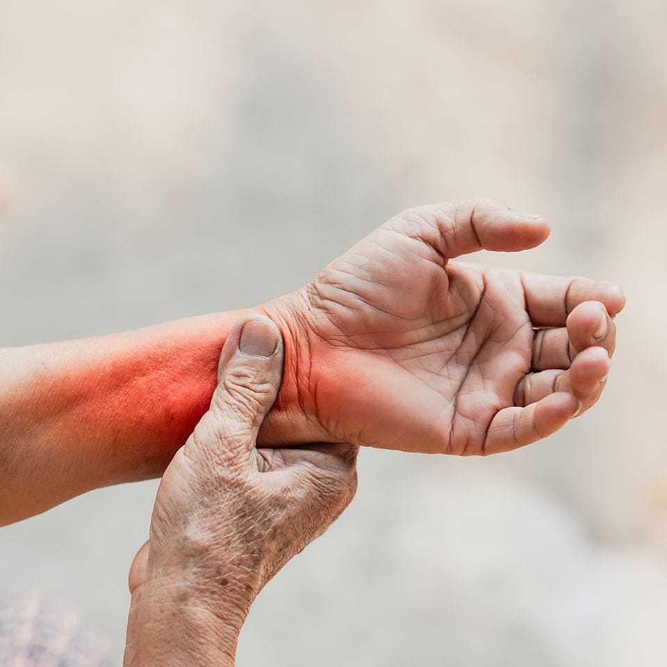 Close-up of an elderly person's hand experiencing wrist pain with a red highlight symbolizing inflammation or arthritis