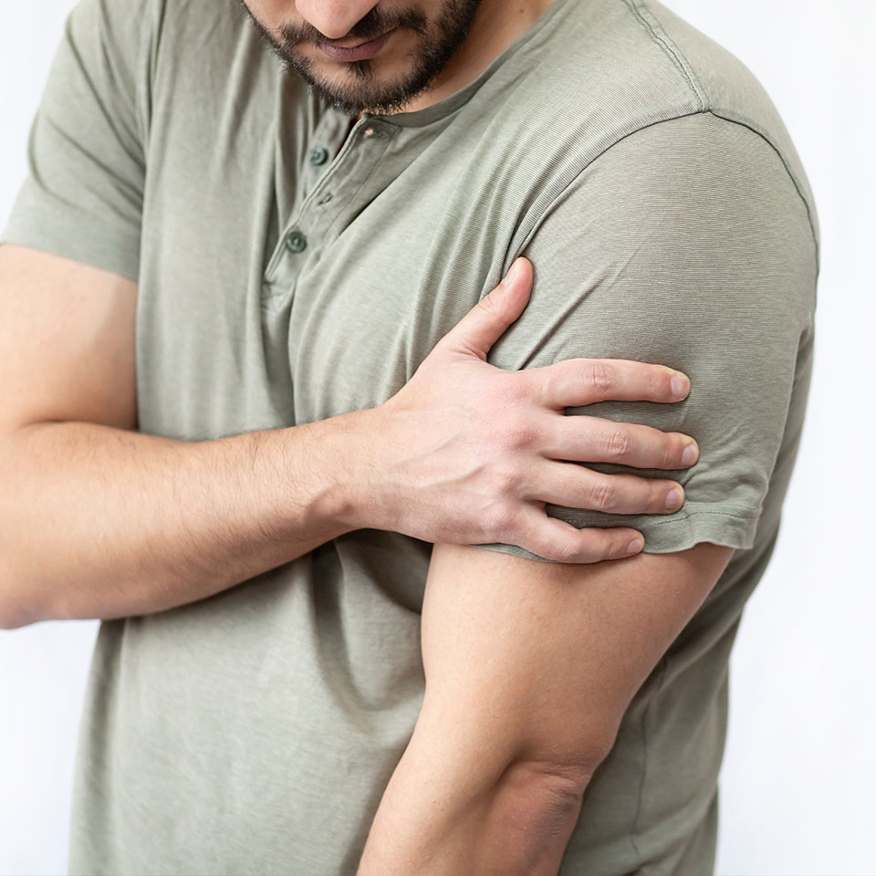 Young man suffering from shoulder pain isolated on white background
