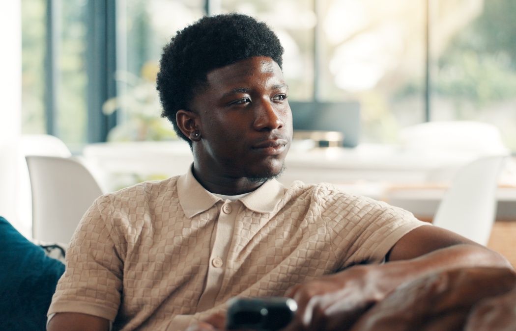 Home, thinking and black man on sofa, smartphone and decision with break, social media and relax. Apartment, cellphone and African person on couch, thoughtful and calm with reflection, app or message